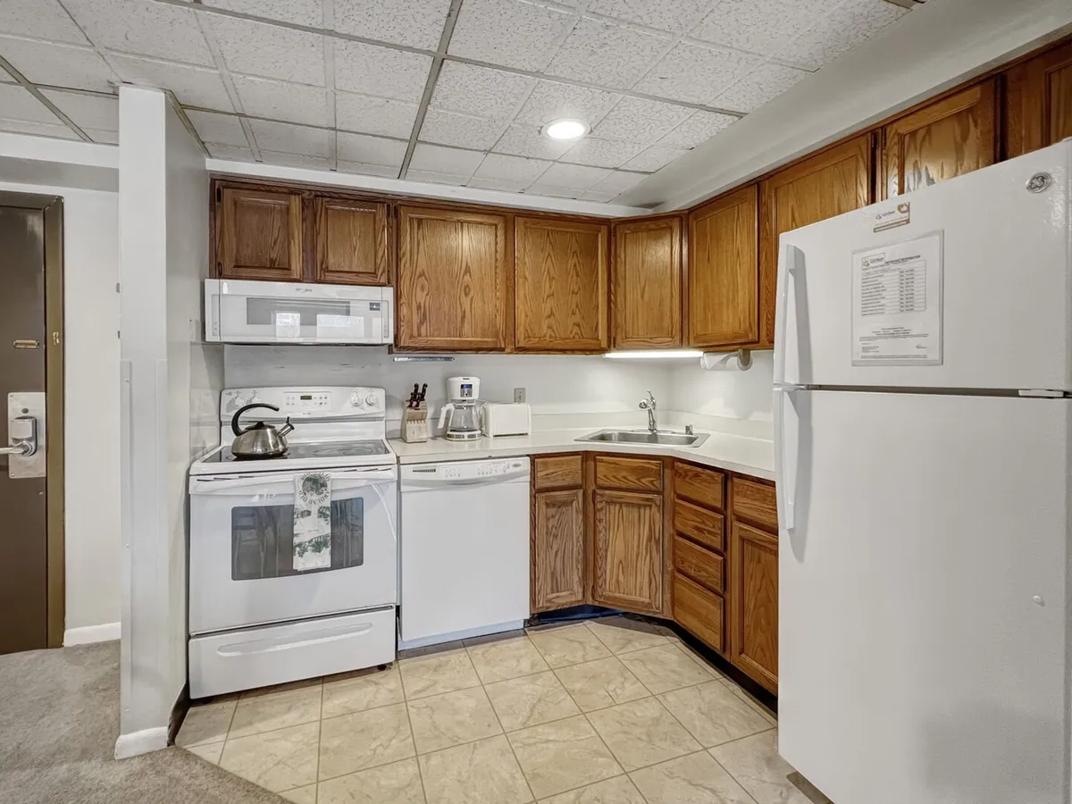 This image showcases a warm, inviting kitchen featuring modern cabinetry, stainless steel appliances, and a spacious sink area. The layout highlights ample counter space, making it ideal for meal prep and social cooking. The scene feels active and family-friendly, suggesting people gathered to cook and share meals together.