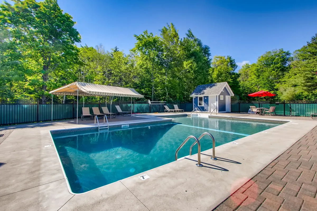 This image presents a tranquil outdoor pool area, complete with cabanas, lounge chairs, lush gardens, and a pool house. The scene is bathed in natural light, evoking a sense of relaxation and enjoyment in the fresh air. The inviting pool and surrounding amenities capture the leisure aspect of the resort’s wellness offerings, particularly in the warmer months.