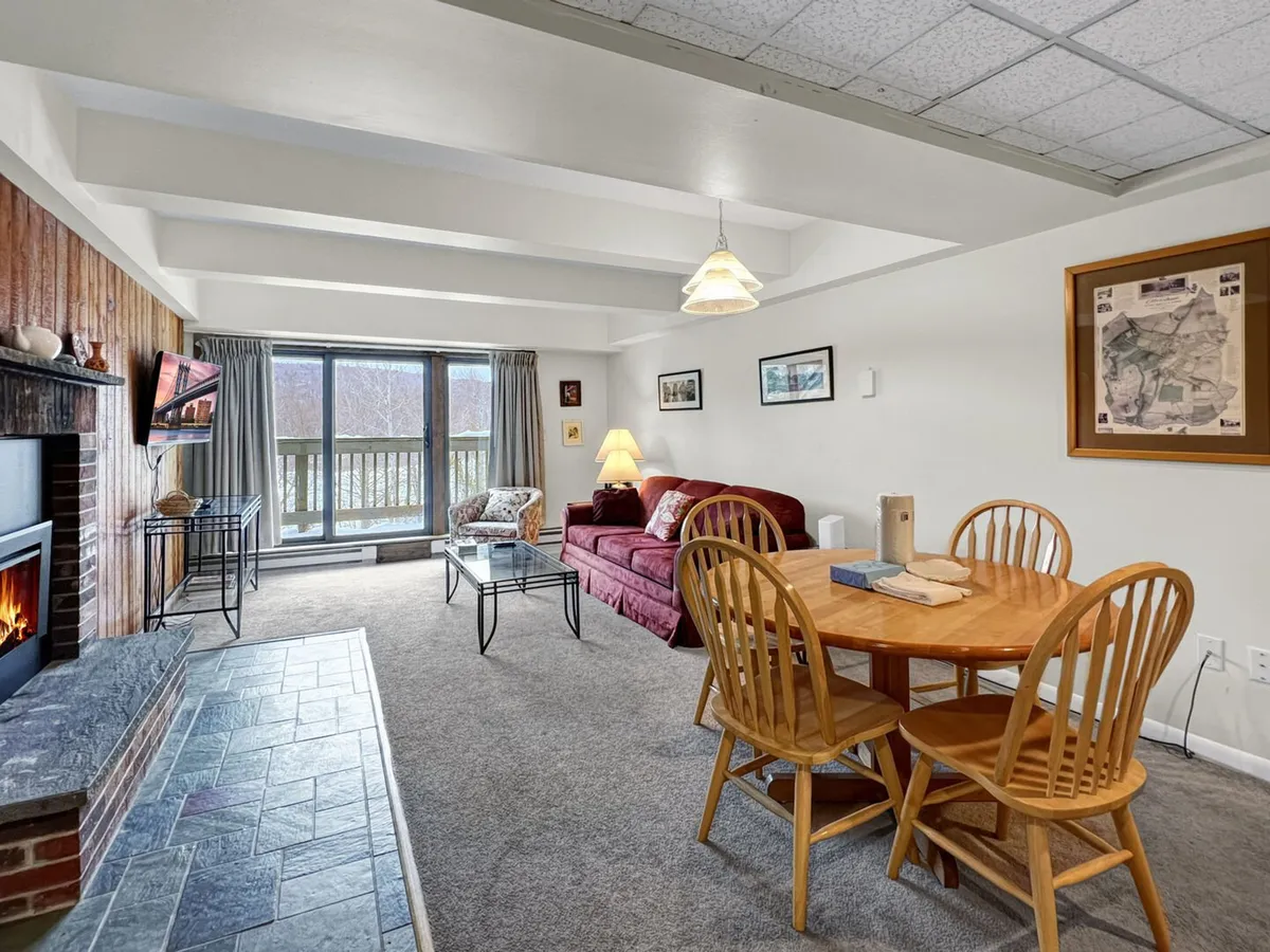 The photo presents a cozy dining area adjacent to a fireplace, with a dining table and comfortable seating. The ambiance is warm and communal, ideal for family meals, board games, or planning adventures. The inclusion of both the table and sofa hints at a multipurpose space for dining and socializing.