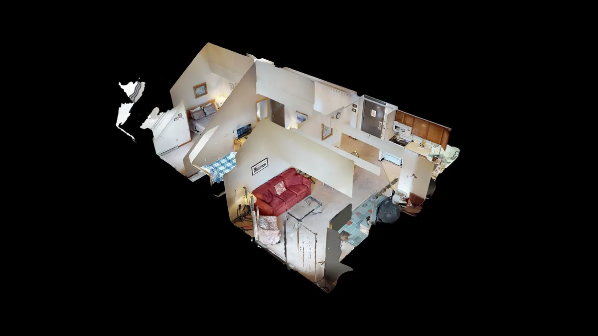 This image captures a cozy open-plan living and dining area with a red couch, a kitchen area in the background, a dining table ready for shared meals, and decorative wall art. The layout supports both relaxation and socializing, with ample natural light and a functional flow between spaces.